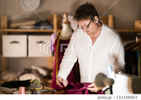 Middle-aged male dressmaker reviewing jeans to restore Middle-aged male dressmaker reviewing jeans to restore 132166601