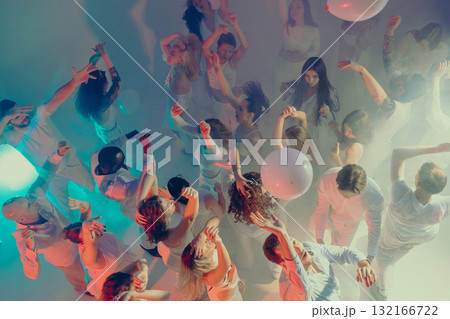 Crowd dancing and celebrating at vibrant white party in smoke light 132166722