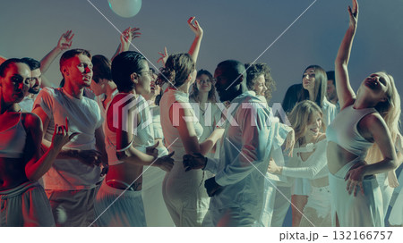 Joyful mixed crowd dancing in rhythm under glowing event lights 132166757