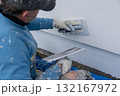 Worker applying plaster to building wall with trowel 132167972