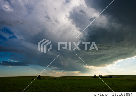 Beautiful scene as storm clouds move across blue skies over lush grassy fields 132168884