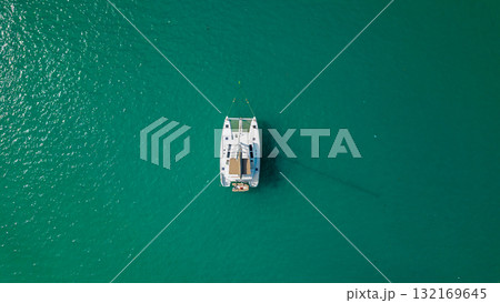 Top down drone view of white sailing catamaran anchored on turquoise lagoon minimal composition calm summer water 132169645