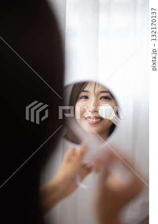 手鏡を見ながらメイクをする若い女性 132170137