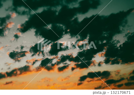 Dramatic sky with dark clouds and a vibrant sunset. The image captures a stunning sunset with dark, ominous clouds contrasting against the warm, orange hues of the setting sun. Twilight skyline. Dramatic sky with dark clouds and a vibrant sunset. The image captures a stunning sunset with dark, ominous clouds contrasting against the warm, orange hues of the setting sun. Twilight skyline. 132170671