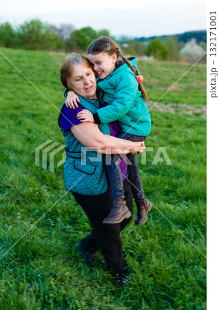 Grandmother and granddaughter sharing a joyful moment outdoors. 132171001