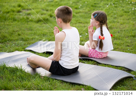 Children practicing mindfulness or yoga outdoors on mats. Peaceful moment of meditation in nature. Children practicing mindfulness or yoga outdoors on mats. Peaceful moment of meditation in nature. 132171014