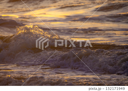 Golden Waves at Sunset A breathtaking view of the ocean during the stunning evening light 132171949
