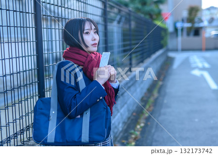 寒い日に部活で登下校する女子高生　冬服でカイロを持ち友達を待つ高校生　登校下校　 132173742