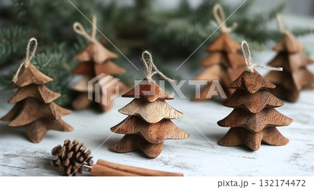 Handcrafted wooden Christmas tree decorations on a white rustic wooden surface with pine branches, representing eco-friendly holiday decor Handcrafted wooden Christmas tree decorations on a white rustic wooden surface with pine branches, representing eco-friendly holiday decor 132174472