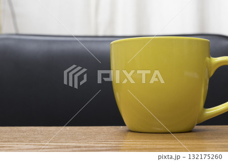 The yellow cup is located on a wooden surface. 132175260