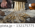 Caucasian female hands making fettuccine noodles using mechanical pasta machine 132175775