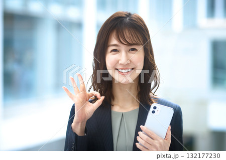 スマホを持ってオッケーサインをするビジネスウーマン 132177230