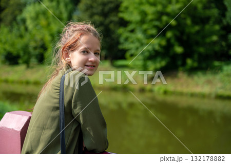 Beautiful teen girl in summer park. Portrait of happy girl smiling in a city park. 132178882