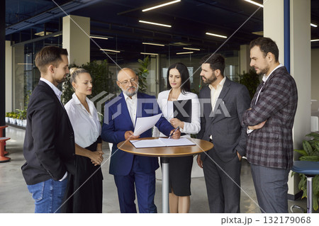 Executive leadership team reviewing documents during formal meeting in open office Executive leadership team reviewing documents during formal meeting in open office 132179068