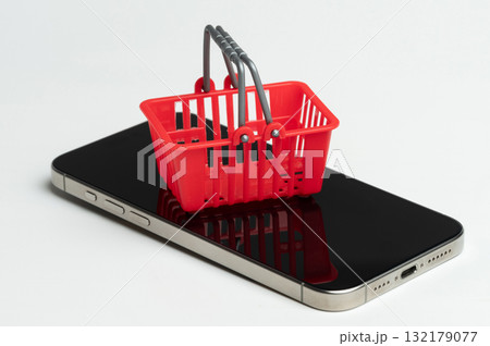 Red shopping basket sits atop mobile phone 132179077