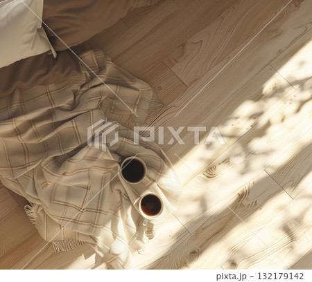 A top-down view of two cups of coffee resting on a folded blanket, illuminated by warm sunlight streaming through a window A top-down view of two cups of coffee resting on a folded blanket, illuminated by warm sunlight streaming through a window 132179142
