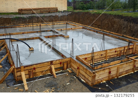 A concrete foundation is being poured on the construction site. Wooden formwork is used. A concrete foundation is being poured on the construction site. Wooden formwork is used. 132179255