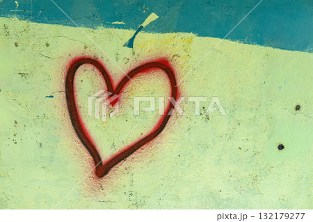 Spray painted red heart on rough pastel wall, bold contrast and raw emotional message in urban setting. Concept of heart symbol, Valentine vibe, love expression in street art 132179277
