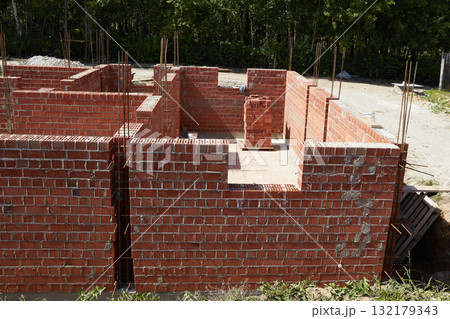 Brick walls rise up at a construction site. House under construction 132179343