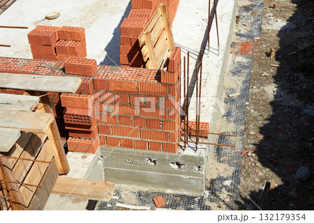 Construction site showcasing brickwork progress on a residential building in a suburban area during daylight 132179354