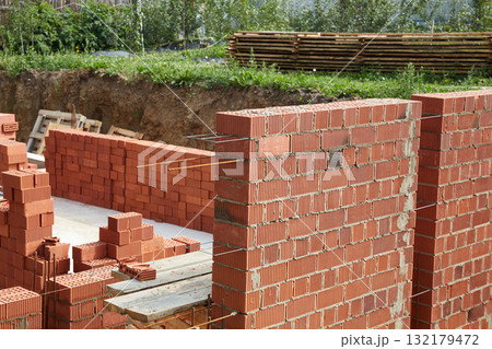 Constructed wall made of red clay bricks is being laid in a pattern. 132179472