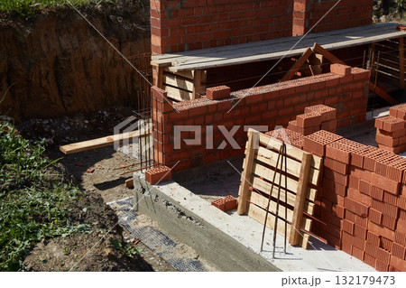 Construction site showcasing brickwork progress on a residential building in a suburban area during daylight 132179473