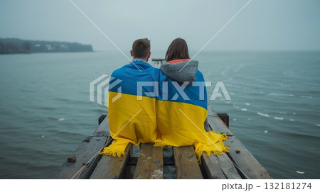 young couple covered with Ukrainian flag, immigration and patriotism concept, russian invasion and Ukraine crisis 132181274