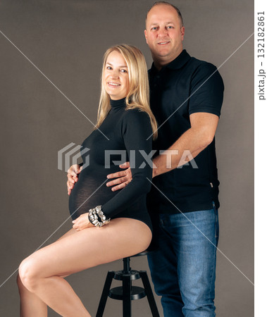 Pregnant woman and her husband posing in studio elegant maternity photo with loving couple awaiting baby 132182861