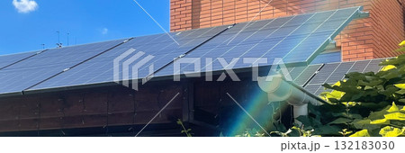 Solar panels on a residential roof generating clean energy under a bright blue sky with sun flare 132183030
