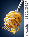 Hyperrealistic macro shot of fork holding spaghetti with herbs and spices against a dark background 132183627