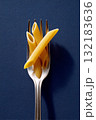 Fork with penne pasta arranged artistically on a dark blue background showcasing culinary elegance 132183636