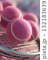 Hyper realistic close-up of pink tennis balls resting on a tennis racket with vibrant textures 132183639
