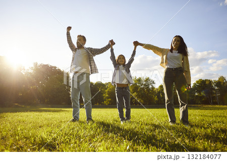 Summer walk in park of happy family, father, mother and kid standing with hands up, holding palms Summer walk in park of happy family, father, mother and kid standing with hands up, holding palms 132184077
