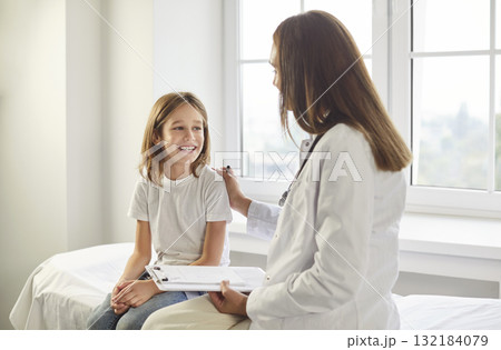 Female doctor talking with a child boy patient during medical examination in clinic. Female doctor talking with a child boy patient during medical examination in clinic. 132184079