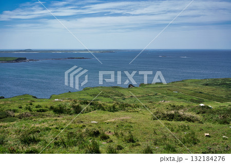 Scenic view of the Irish coast on a sunny day, with lush green hills overlooking the ocean. 132184276