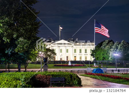 The White House, the official residence of the U.S. President, viewed from Lafayette Square in Washington, D.C. The historic neoclassical building with a United States flag are illuminated at night 132184764