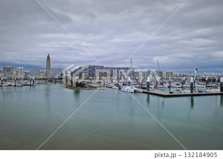 The marina and port of Le Havre with numerous boats and yachts moored, flanked by modern waterfront architecture, the Tour Saint-Joseph and the curved buildings of the Docks Vauban 132184905