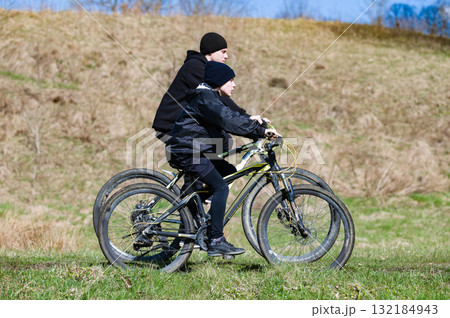 Two cyclists enjoy a ride through a grassy field on a sunny day. A beautiful outdoor adventure. 132184943