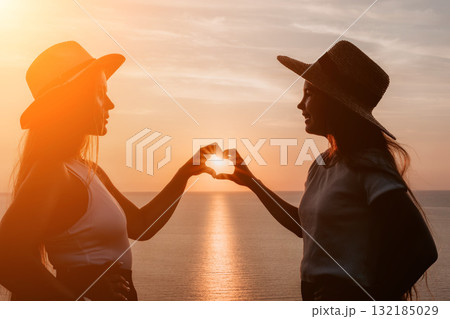 Silhouettes of Two Women Making a Heart Shape with their Hands at Sunset Silhouettes of Two Women Making a Heart Shape with their Hands at Sunset 132185029