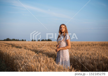 Young dreamy girl in field of ripe rye. Portrait of beautiful girl in field of wheat admiring the beauty of nature Young dreamy girl in field of ripe rye. Portrait of beautiful girl in field of wheat admiring the beauty of nature 132185270