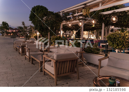 Outdoor seating area with wooden chairs and ambient lighting in a cozy evening atmosphere 132185598