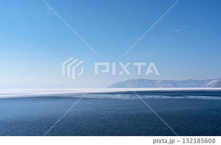 Serene blue waters reflecting clear skies with distant mountains and tranquil ambiance Serene blue waters reflecting clear skies with distant mountains and tranquil ambiance 132185608
