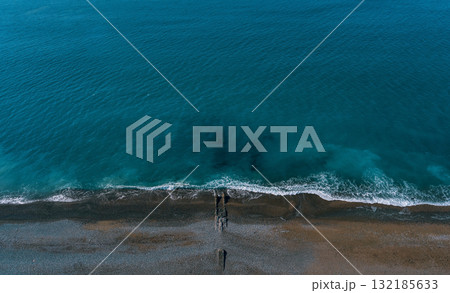 Aerial view of tranquil ocean waves gently lapping against a sandy beach shoreline Aerial view of tranquil ocean waves gently lapping against a sandy beach shoreline 132185633