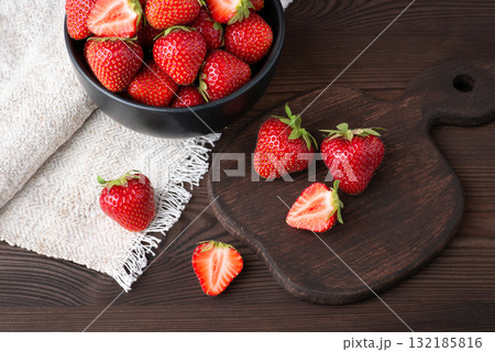 Beautiful ripe strawberry on the table. Studio shot of red strawberry berries on dark table with cutting board and white towel 132185816