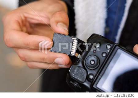 Male photographer putting a flash card into the camera. Technology, professional shooting, close up, details. Male photographer putting a flash card into the camera. Technology, professional shooting, close up, details. 132185830