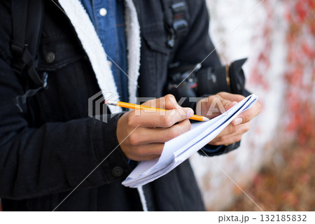 Young boy with notebook and pencil making sketches. Male enthusiast photographer in the park searching for inspiration. 132185832