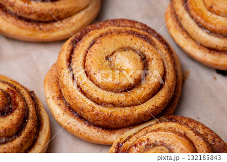 Many fresh baked buns with cinnamon on baking paper. Cooking tasty bakery at home 132185843