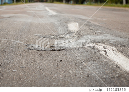 Overloaded truck ruined asphalt road and made its rusfase uneven with bumps 132185856