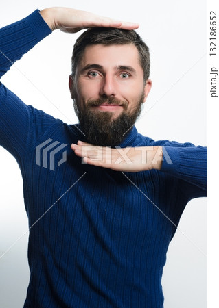 Bearded man framing his face with hands against a white background. 132186652