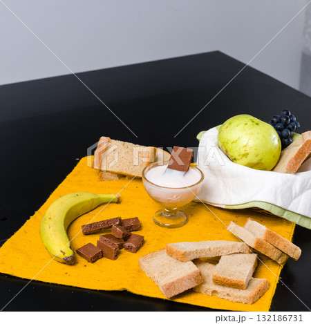 Simple breakfast spread with fruit, bread, yogurt, and chocolate. Simple breakfast spread with fruit, bread, yogurt, and chocolate. 132186731